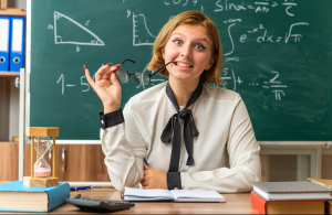 Une enseignante en école primaire accompagne un élève durant un exercice en classe, illustrant la reconversion professionnelle vers le professorat des écoles.